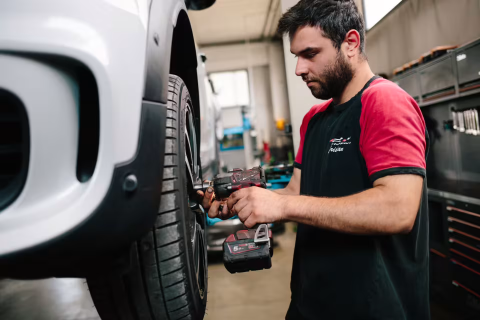 Meccanico di LR Motorsport avvita i bulloni della ruota di un'auto con l'avvitatore