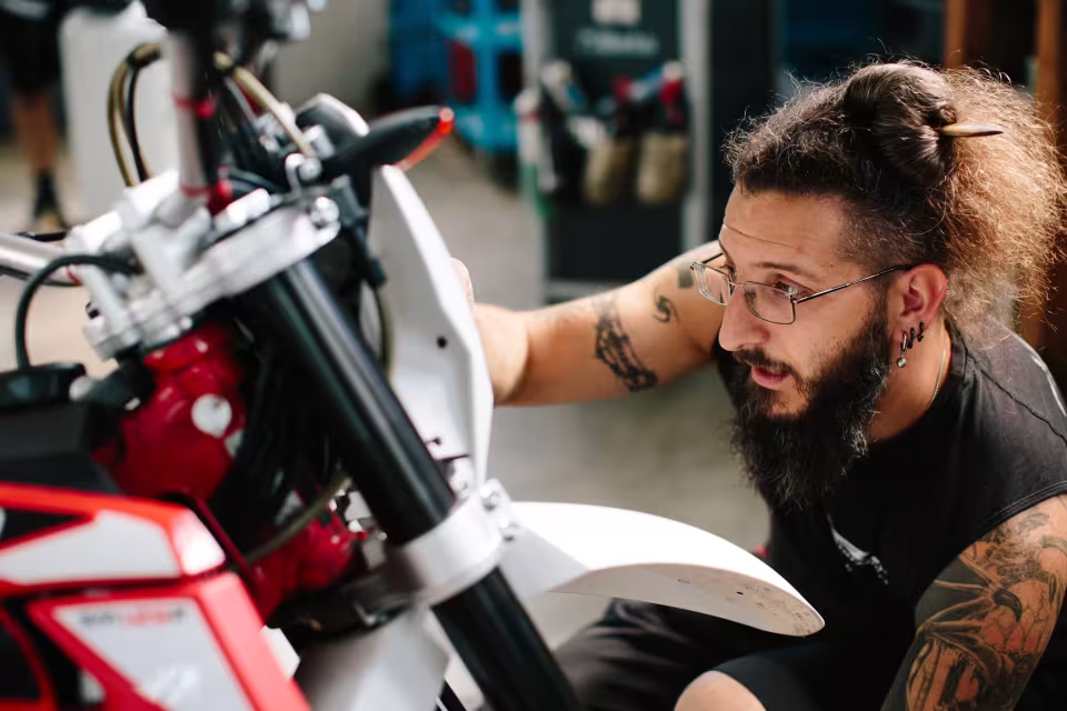 Meccanico di LR Motorsport al lavoro sulla forcella di una moto durante una riparazione meccanica
