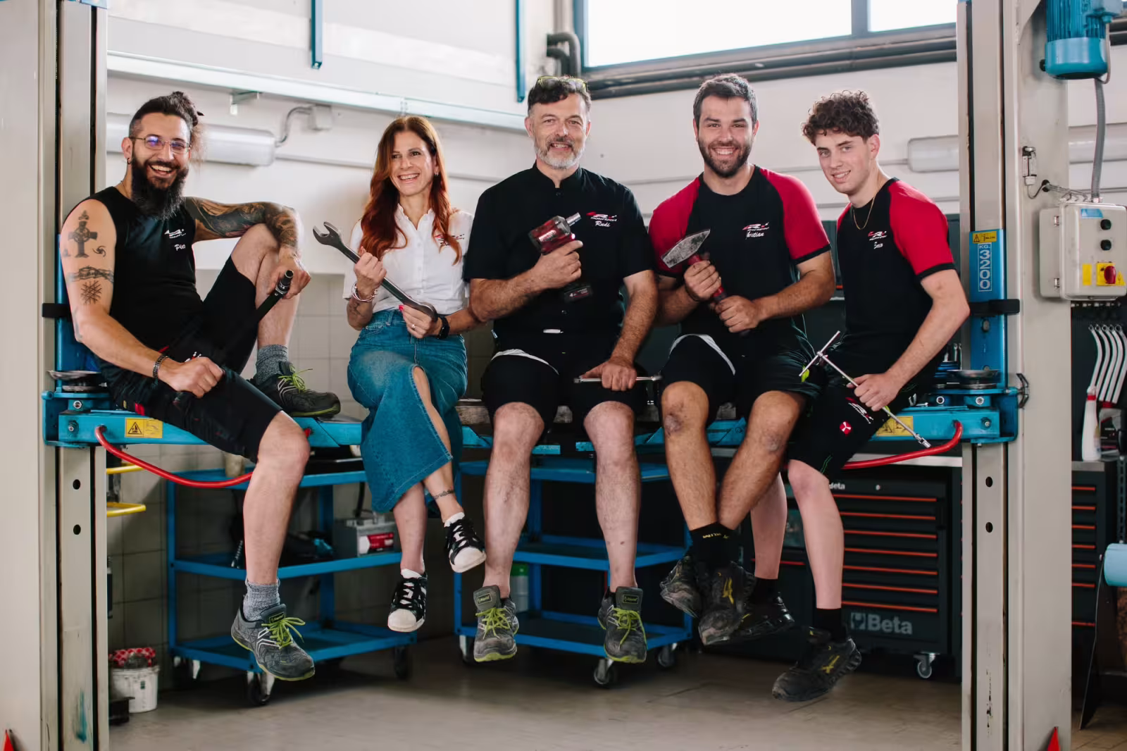 Il team dell'autofficina LR Motorsport sorride nell'officina di Ponte nelle Alpi